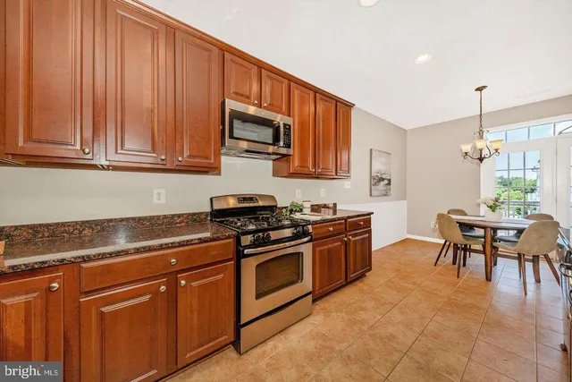 a kitchen with stainless steel appliances granite countertop a stove a sink dishwasher and a microwave oven with white cabinets