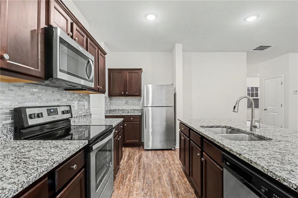 4635 Bluffton Court Cumming, GA 30028 - Photo 11 of 27 a kitchen with stainless steel appliances granite countertop a sink stove and refrigerator