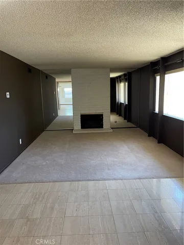 an empty room with windows and fireplace
