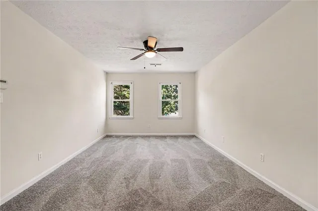 an empty room with windows and fan