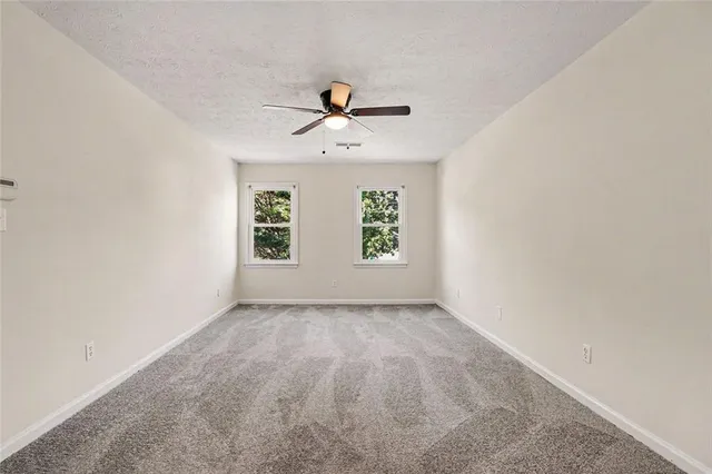 an empty room with windows and fan