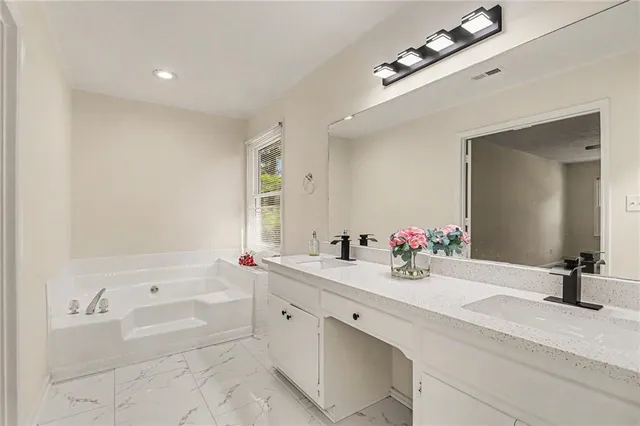 a bathroom with a sink vanity tub and a mirror