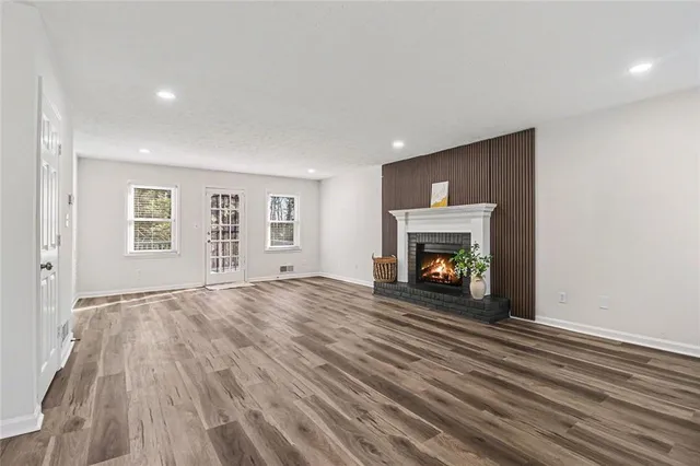 a view of an empty room with wooden floor fireplace and a window