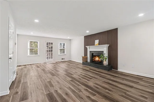 a view of an empty room with wooden floor fireplace and a window