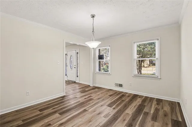 a view of an empty room with window and wooden floor