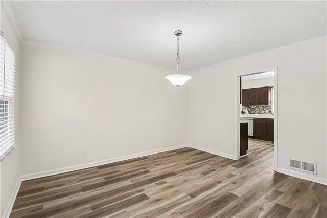 a view of empty room with wooden floor and window