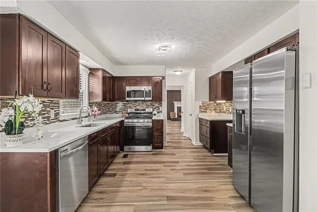 a kitchen with stainless steel appliances granite countertop a refrigerator a stove top oven a sink dishwasher and wooden cabinets