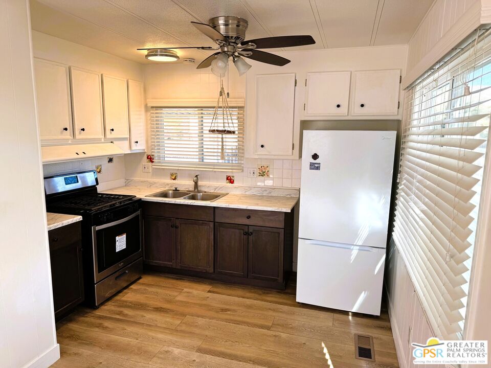 17850 Corkill Road, Unit 94 Desert Hot Springs, CA 92241 - Photo 7 of 39 a kitchen with stainless steel appliances granite countertop a refrigerator a sink a stove a microwave and island with wooden floor