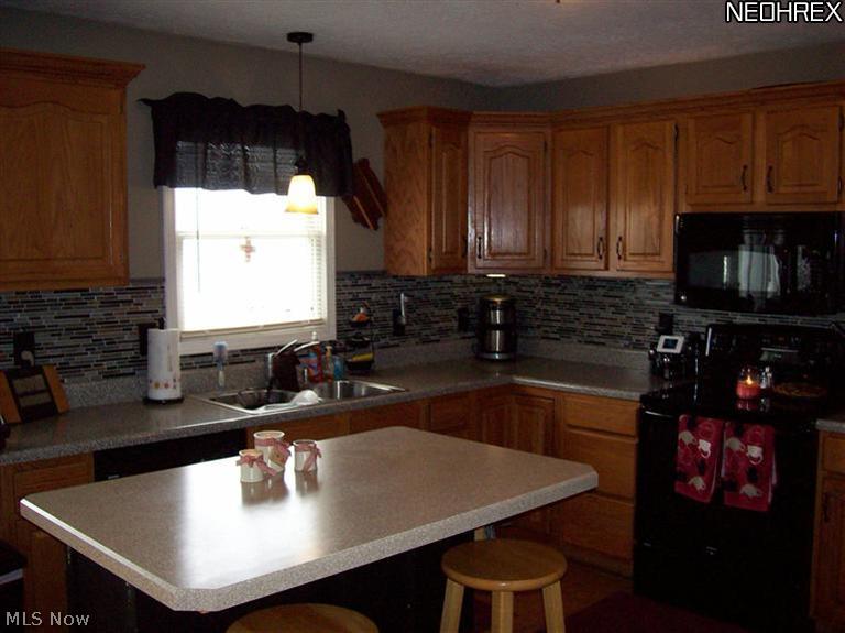 8245 Ruff Road West Salem, OH 44287 - Photo 8 of 25 Kitchen has a new back splash (2013), breakfast bar, raised oak cabinetry and newer appliances.(2012) All kitchen appliances will stay. That makes it convenient!!!
