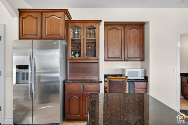 4768 East Hickman Canyon Road Stockton, UT 84071 - Photo 14 of 85 Kitchen featuring stainless steel refrigerator with ice dispenser, dark stone counters, glass insert cabinets.