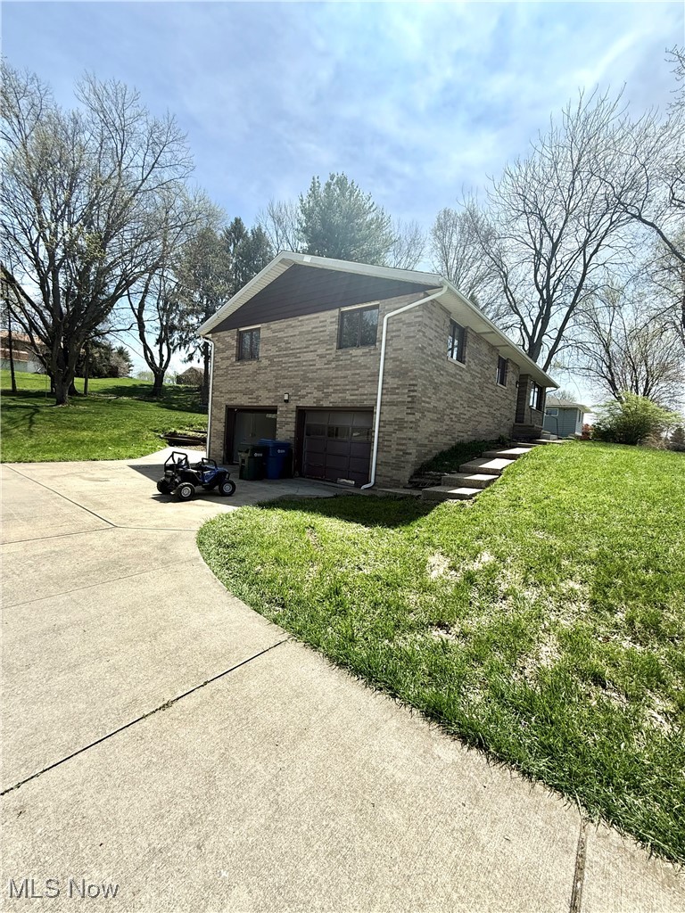 4669 Mars Road Uniontown, OH 44685 - Photo 5 of 31 View of side of home with an attached garage, a yard, and concrete driveway