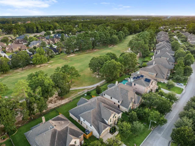 an aerial view of residential houses with outdoor space and trees