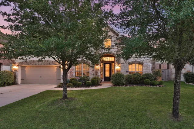 front view of a brick house with a large windows and a flower plants