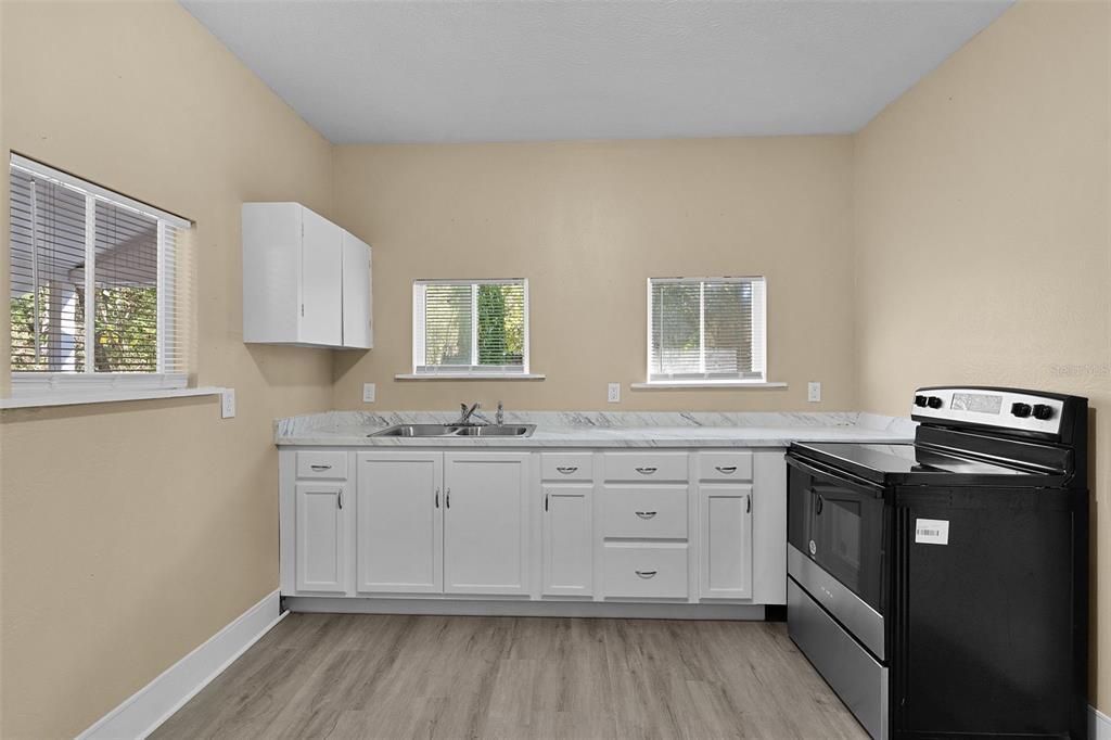 2245 Northwest 63rd Place Ocala, FL 34475 - Photo 17 of 38 a kitchen with granite countertop white cabinets sink and stainless steel appliances