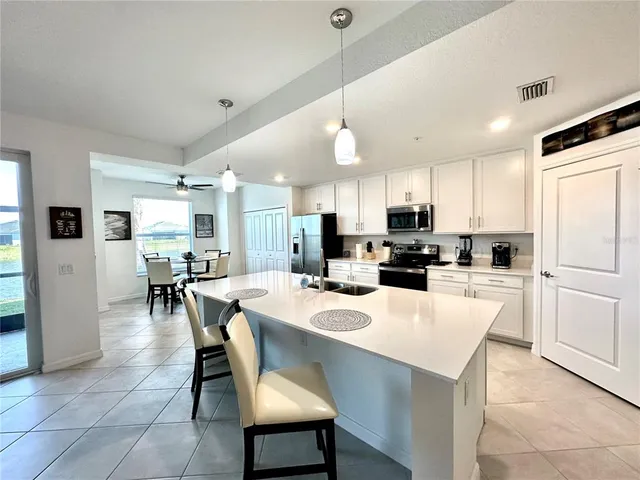 a kitchen with a dining table chairs refrigerator and microwave