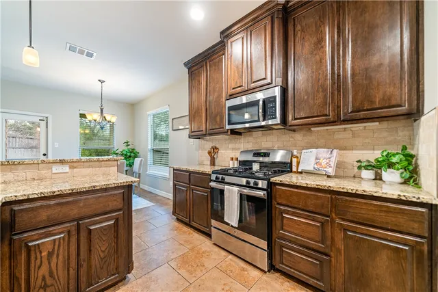 a kitchen with granite countertop cabinets stainless steel appliances and a counter space