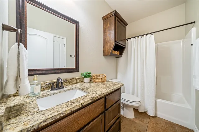 a bathroom with a granite countertop sink a mirror and a toilet
