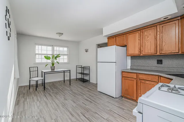 a kitchen with stainless steel appliances a refrigerator a stove a sink and a dining table with wooden floor