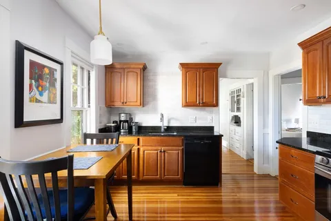 a large kitchen with granite countertop a stove a sink a refrigerator and wooden cabinets