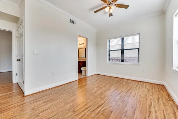 an empty room with wooden floor chandelier fan and windows