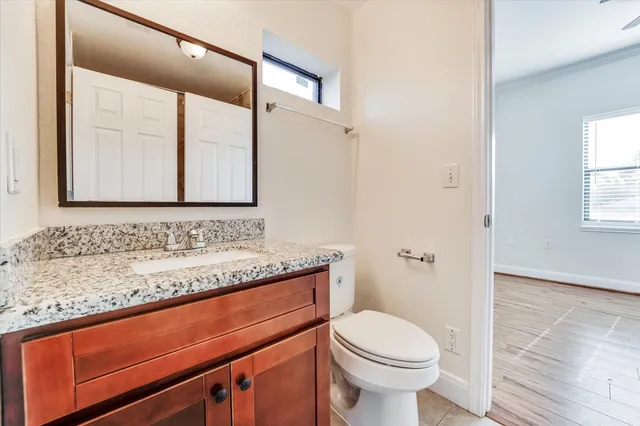 a bathroom with a granite countertop sink toilet and mirror