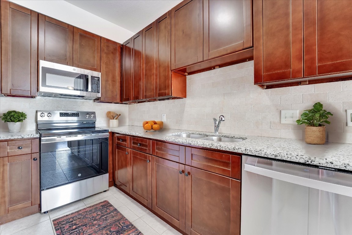 10102 Neuens Road, Unit A103 Houston, TX 77080 - Photo 7 of 23 a kitchen with granite countertop stainless steel appliances wooden cabinets and a sink