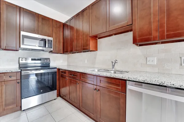 a kitchen with granite countertop stainless steel appliances wooden cabinets and a sink