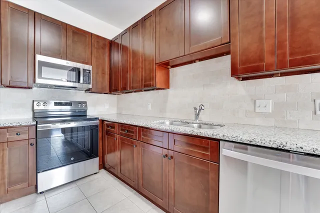 a kitchen with granite countertop stainless steel appliances wooden cabinets and a sink