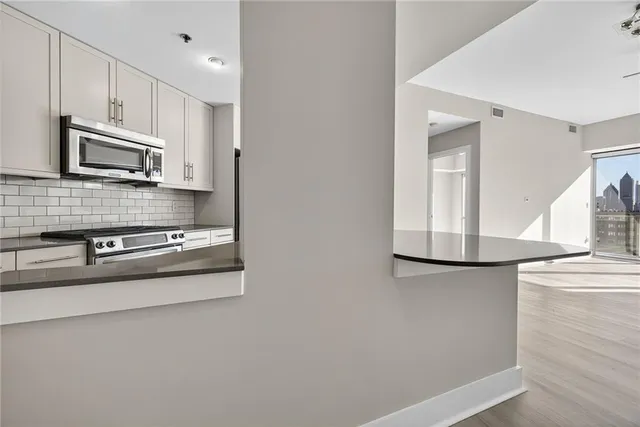 a kitchen with stainless steel appliances granite countertop white cabinets a microwave a sink and a refrigerator