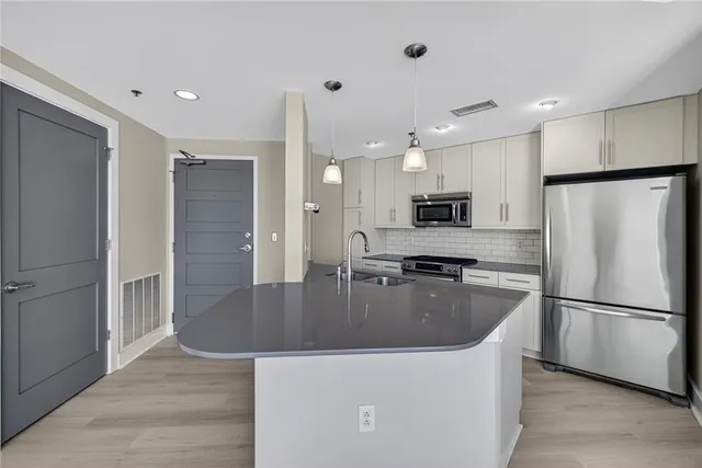 a kitchen with stainless steel appliances granite countertop a refrigerator a sink a stove and a refrigerator