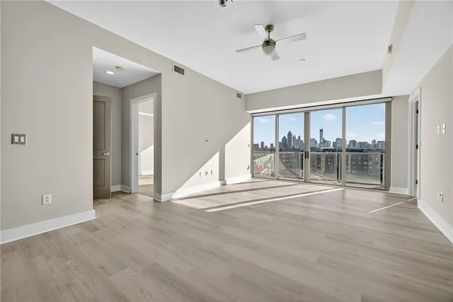 a view of empty room with wooden floor and fan