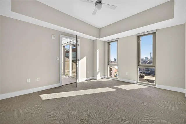 an empty room with windows and ceiling fan