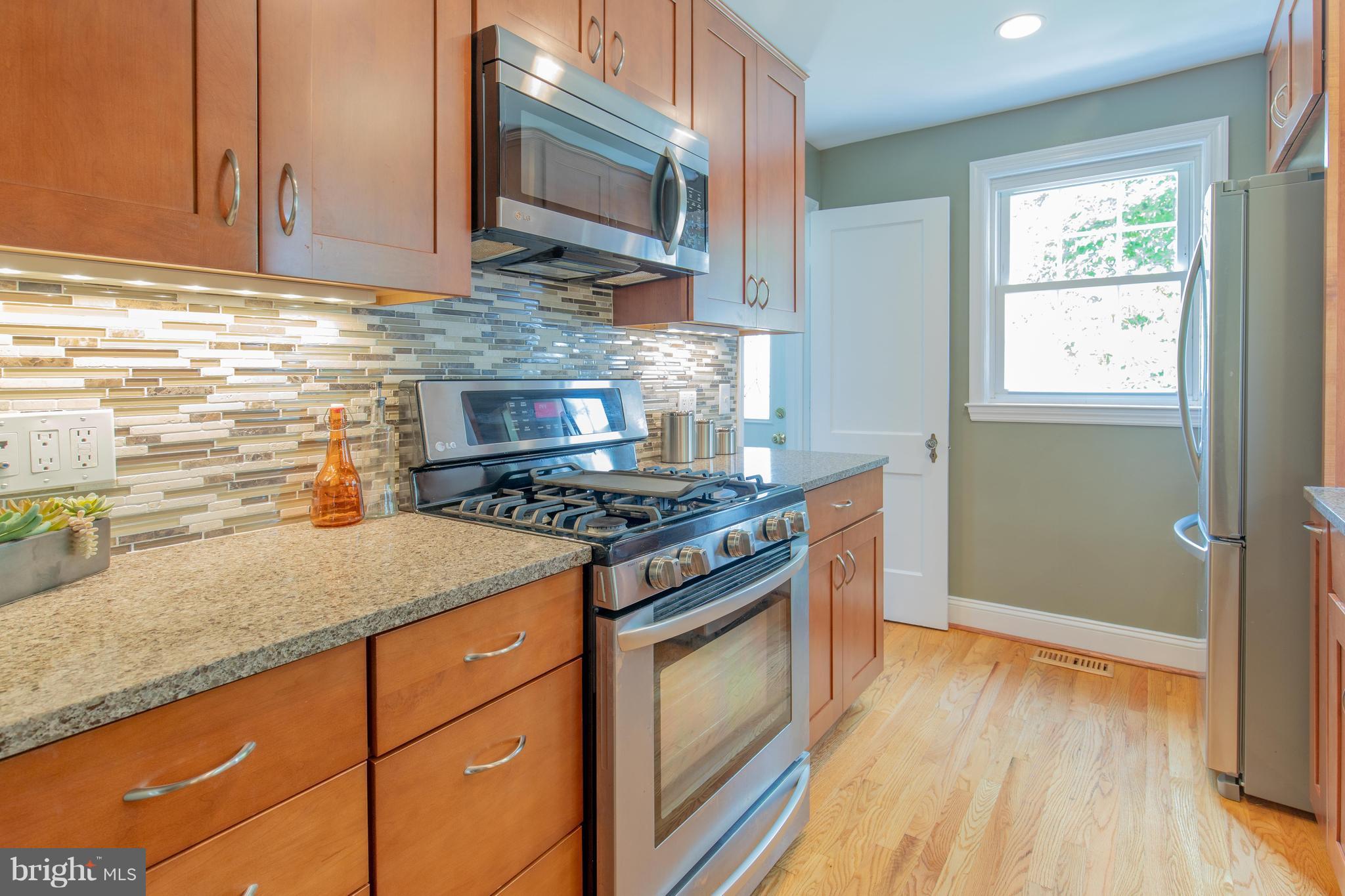 9105 Flower Avenue Silver Spring, MD 20901 - Photo 11 of 30 a kitchen with stainless steel appliances granite countertop a stove and a microwave