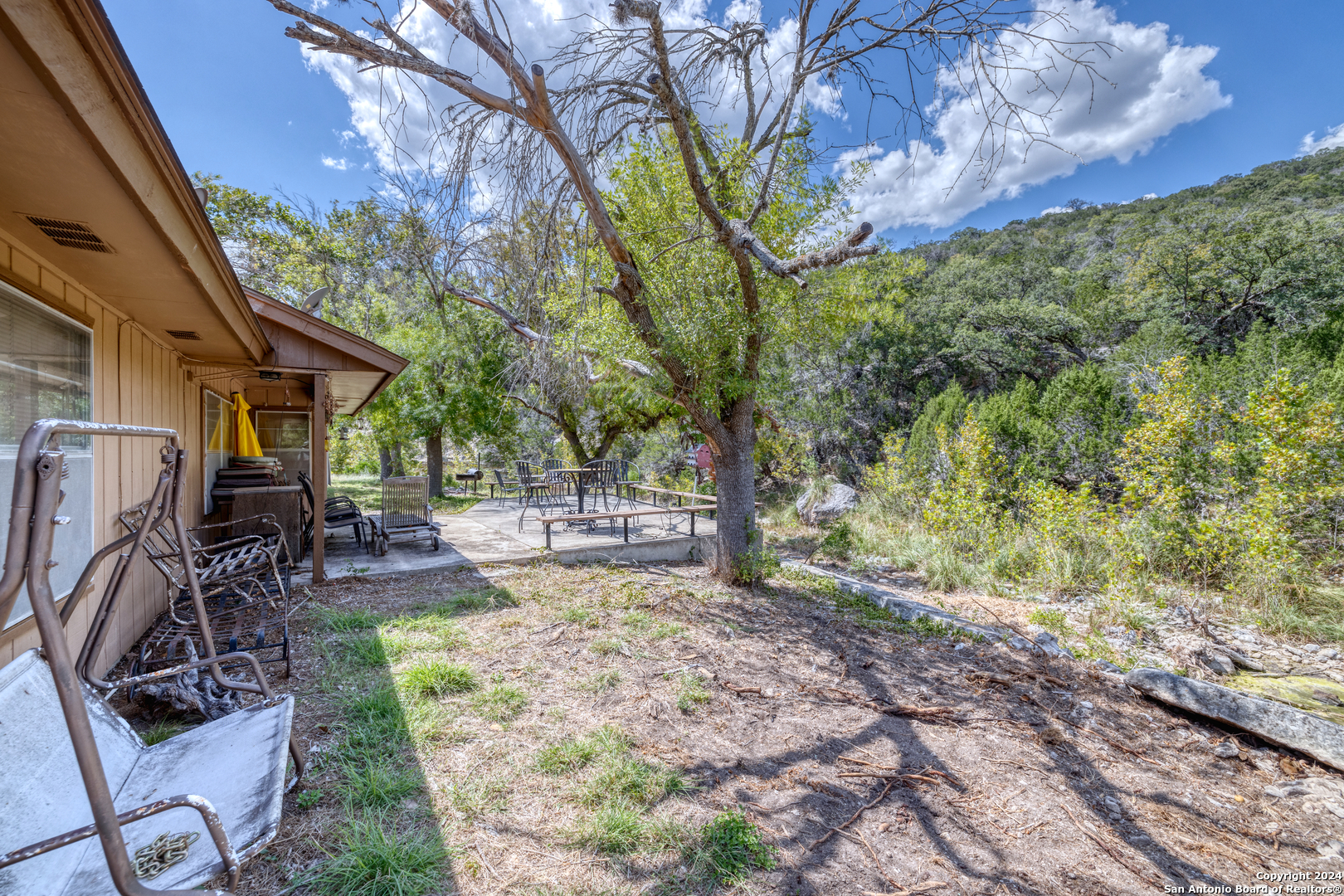 2227 Mill Creek Road Leakey, TX 78873 - Photo 3 of 20 a view of a backyard with table and chairs and a large tree