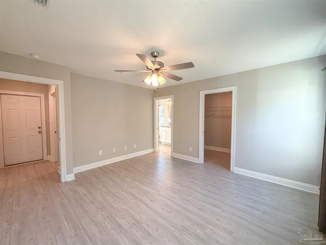 an empty room with wooden floor and ceiling fan