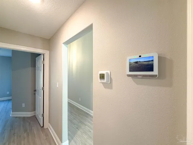 a view of a hallway with wooden floor and a bathroom