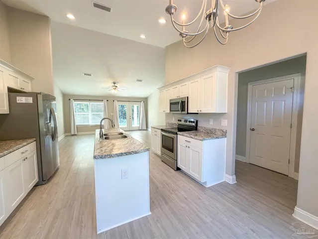 a large kitchen with stainless steel appliances granite countertop a lot of counter space and wooden floor