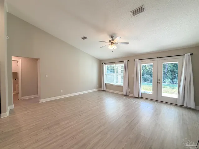 a view of an empty room with a window and wooden floor