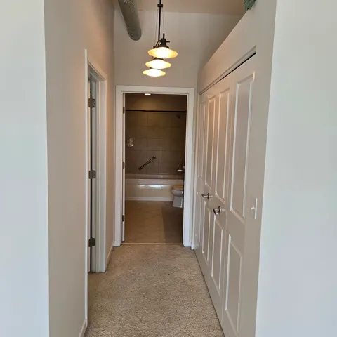 a view of a hallway with a livingroom and a bathroom with sink