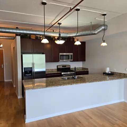 a kitchen with stainless steel appliances granite countertop a sink a stove and a wooden floors