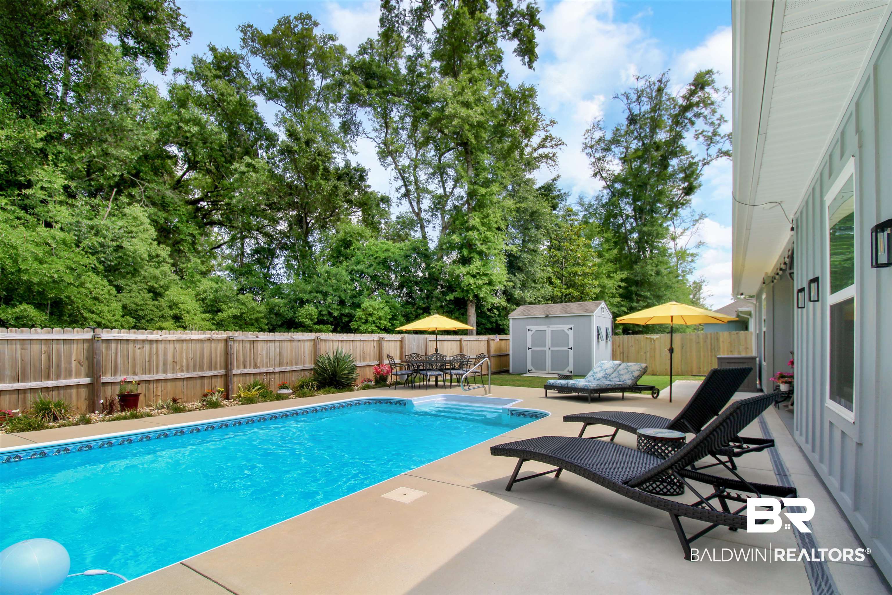 1885 Carly Street Foley, AL 36535 - Photo 29 of 40 Expansive backyard featuring a rectangular swimming pool, concrete patio, privacy fencing, and mature trees