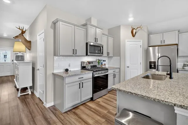 a kitchen with granite countertop white cabinets and stainless steel appliances