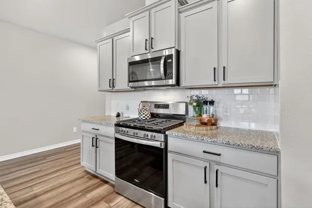 a kitchen with stainless steel appliances granite countertop white cabinets and a stove a oven with white countertops