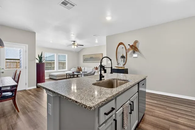 a kitchen with a sink and a stove with wooden floor