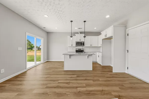 a kitchen with kitchen island white cabinets stainless steel appliances a sink and a refrigerator