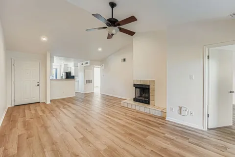a view of a livingroom with a fireplace a ceiling fan and wooden floor