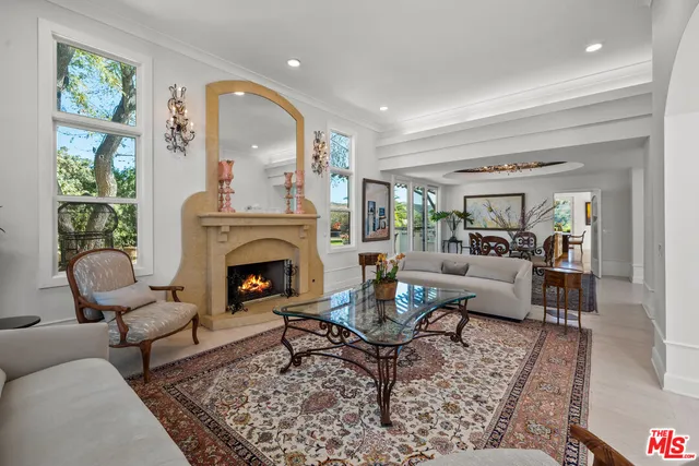 a living room with furniture a rug a fireplace and a large window