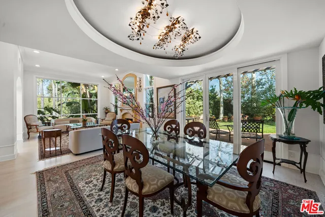 a dining room with furniture floor to ceiling windows and a chandelier