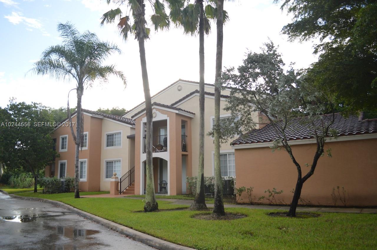 2011 Renaissance Boulevard, Unit 201 Miramar, FL 33025 - Photo 22 of 22 a view of a white house next to a yard and palm trees