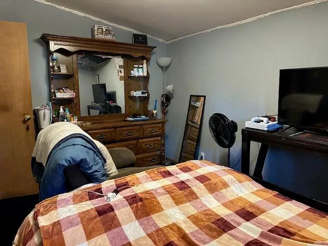a bedroom with a bed and a flat tv screen on dresser